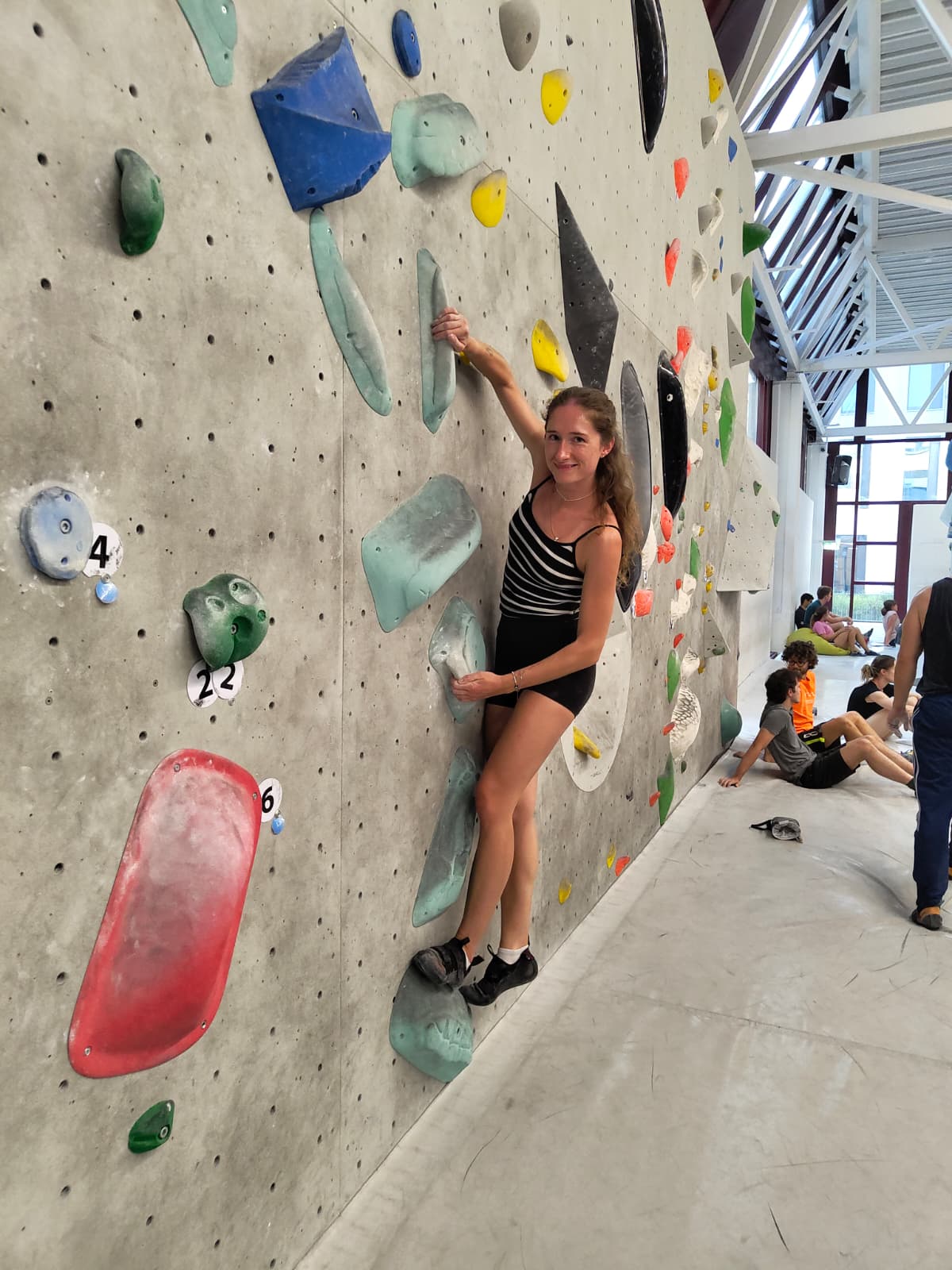 Naomi climbing on an indoor bouldering wall.