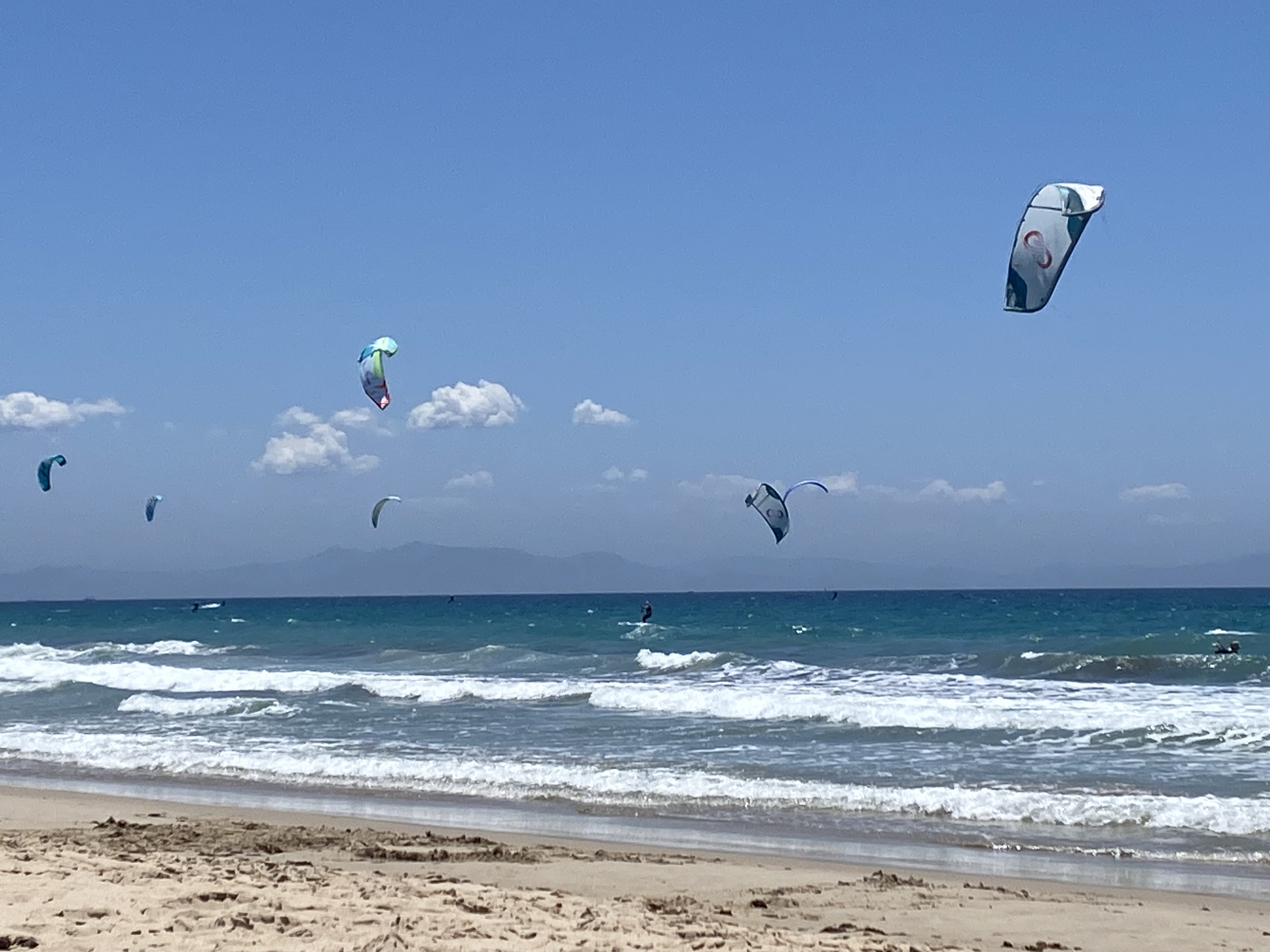 Kitesurfing on open water under a pale sky.
